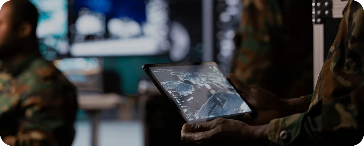 Soldier holding a rugged tablet with a digital terrain map for field survey and positioning